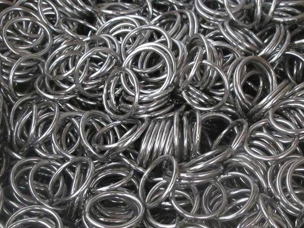 Many stainless steel round rings in a box for wire rope.