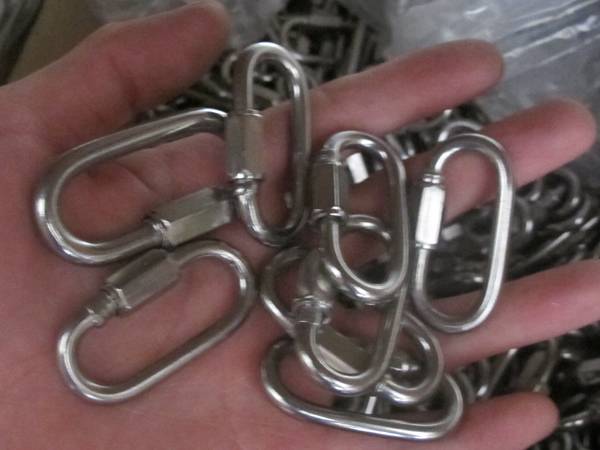 Eight stainless steel wire rope quick links on a hand.
