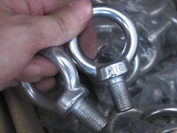 Two stainless steel eye bolts in a hand.